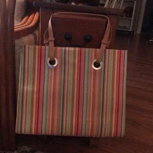 Multi colored striped shoulder bag w/grommets holding tan leather straps